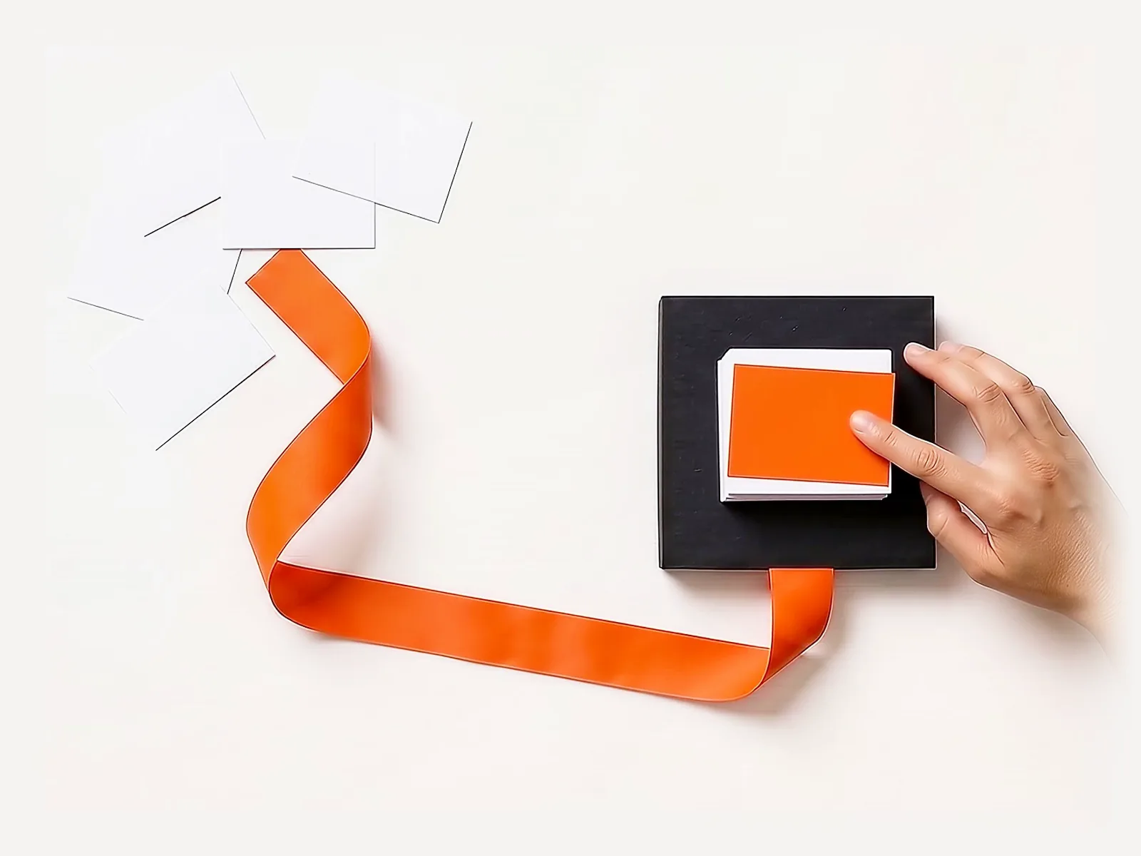 Tarjetas de papel sueltas avanzan por una cinta naranja y se ordenan en una sola pila sobre una base negra, donde una mano presiona la tarjeta naranja de arriba.